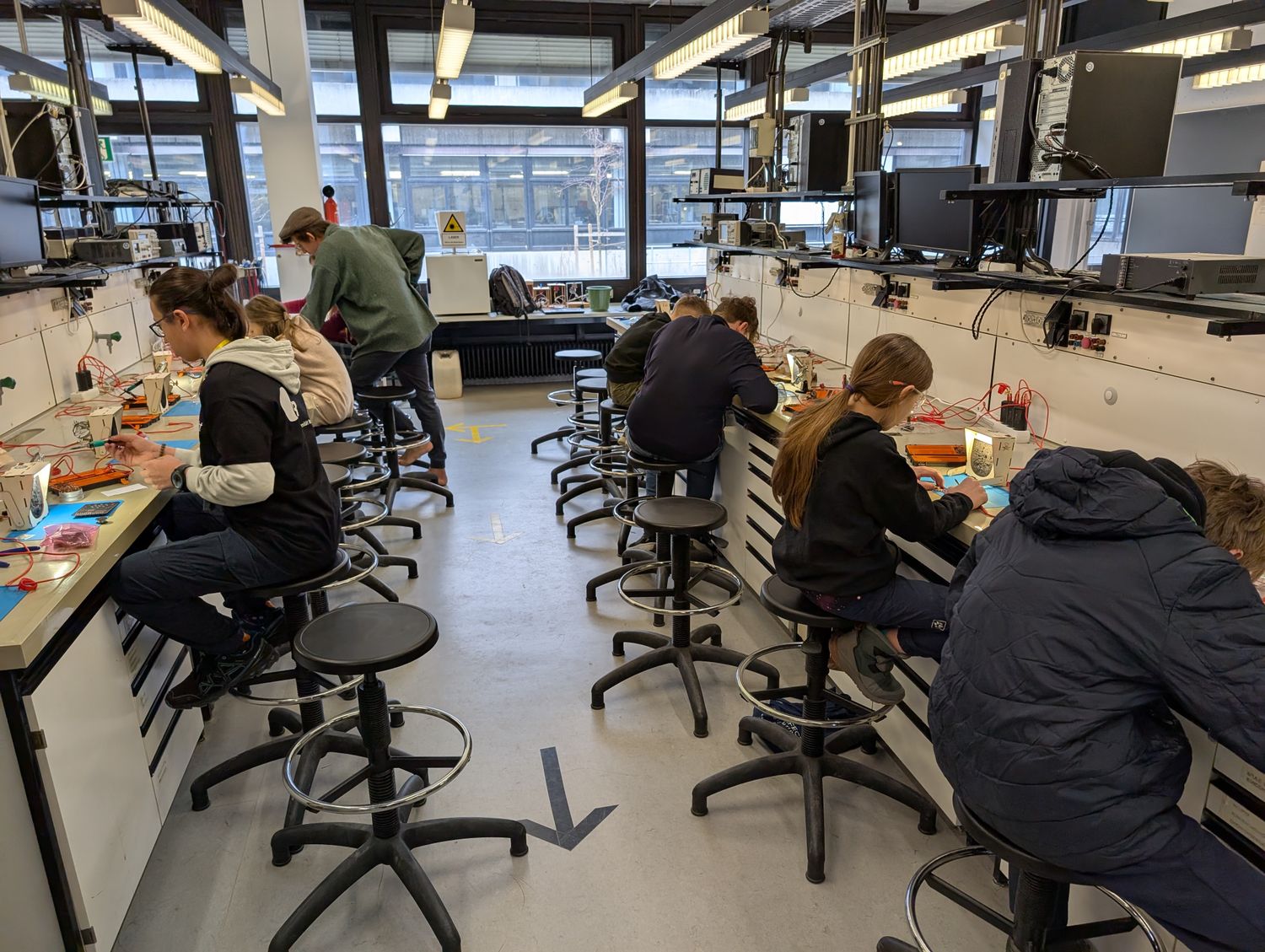 Eine Reihe Kinder in einem Labor, die am Löten sind